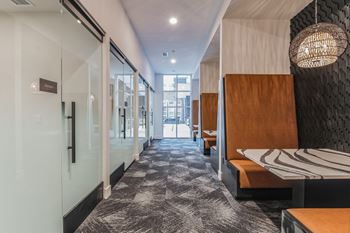 A long hallway with tables and chairs and glass doors
